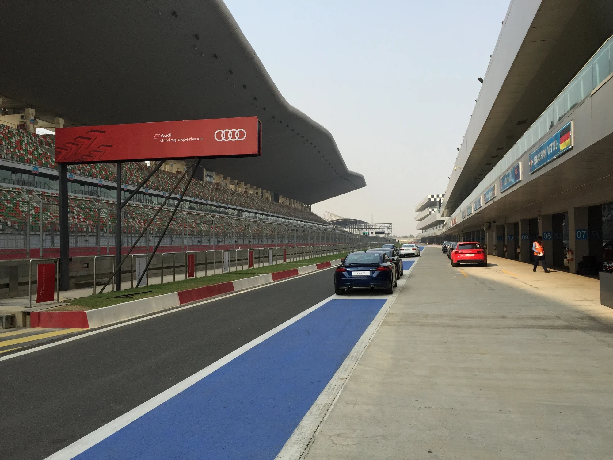 Pit lane line-up under the red Audi driving experience banner at the Buddh International Circuit