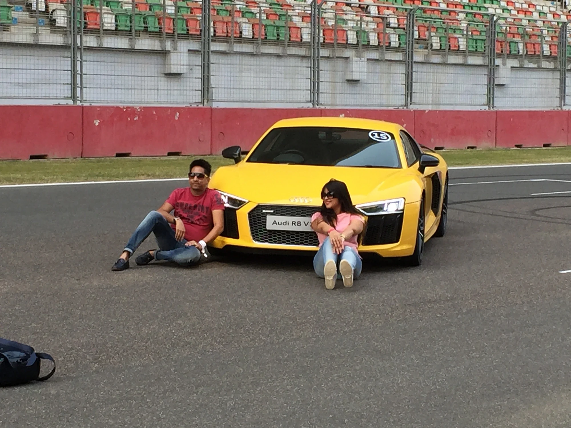 Guests posing on the track with the yellow Audi R8 sports car