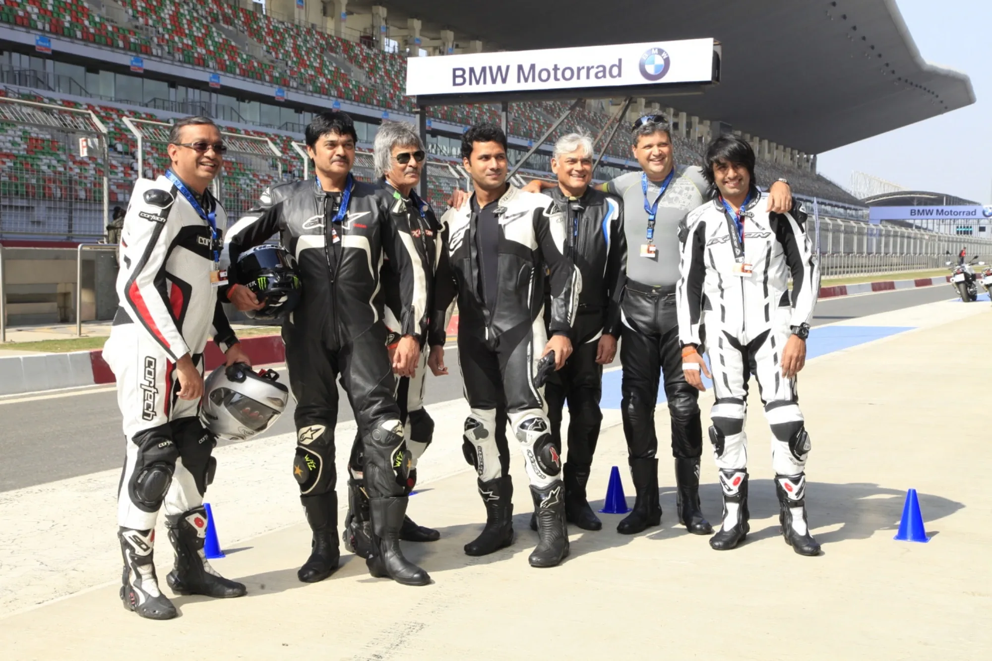 BMW motorcycle owners group photo in racing leathers under the Motorrad gantry