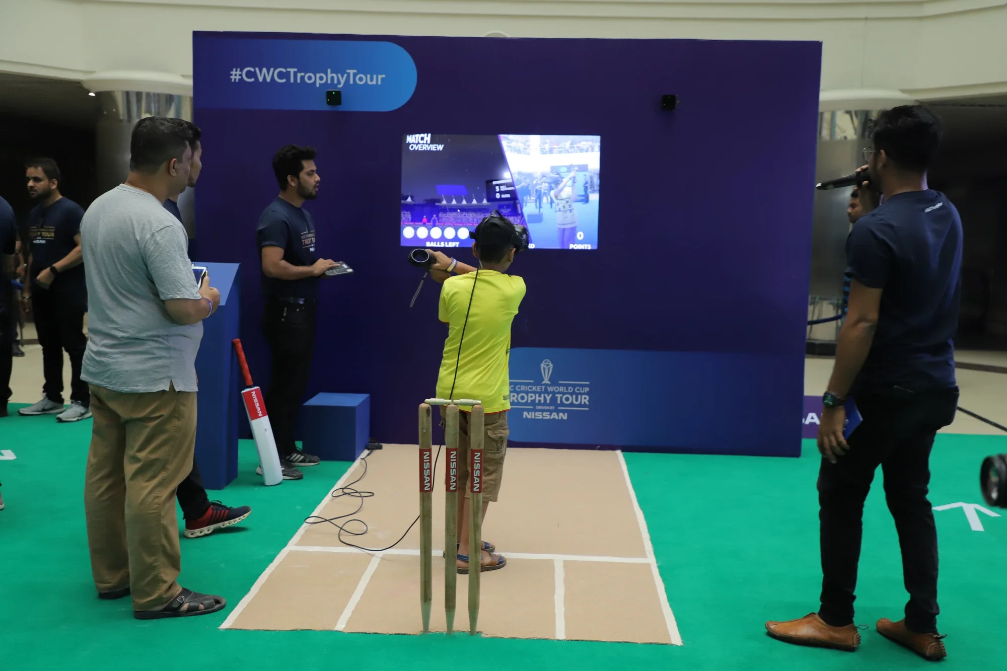 Young fan playing VR Cricket beside the branded stumps at the Trophy Tour