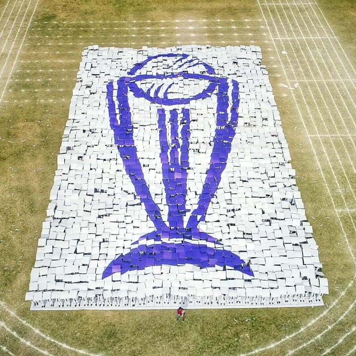 Aerial view of the giant ICC World Cup trophy card mosaic formed by participants on a field