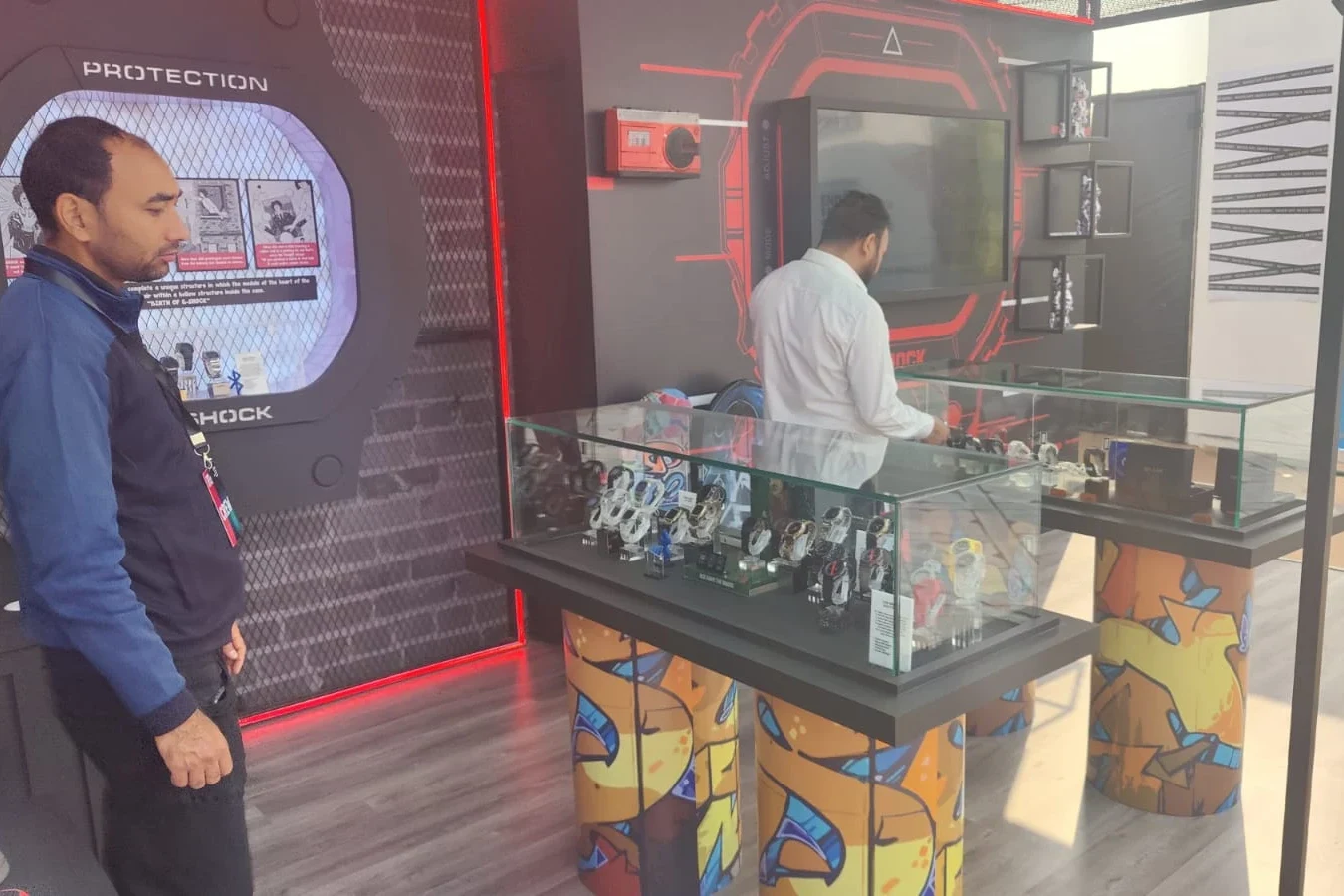 G-SHOCK pavilion interior — PROTECTION display wall and glass watch showcases with graffiti bases