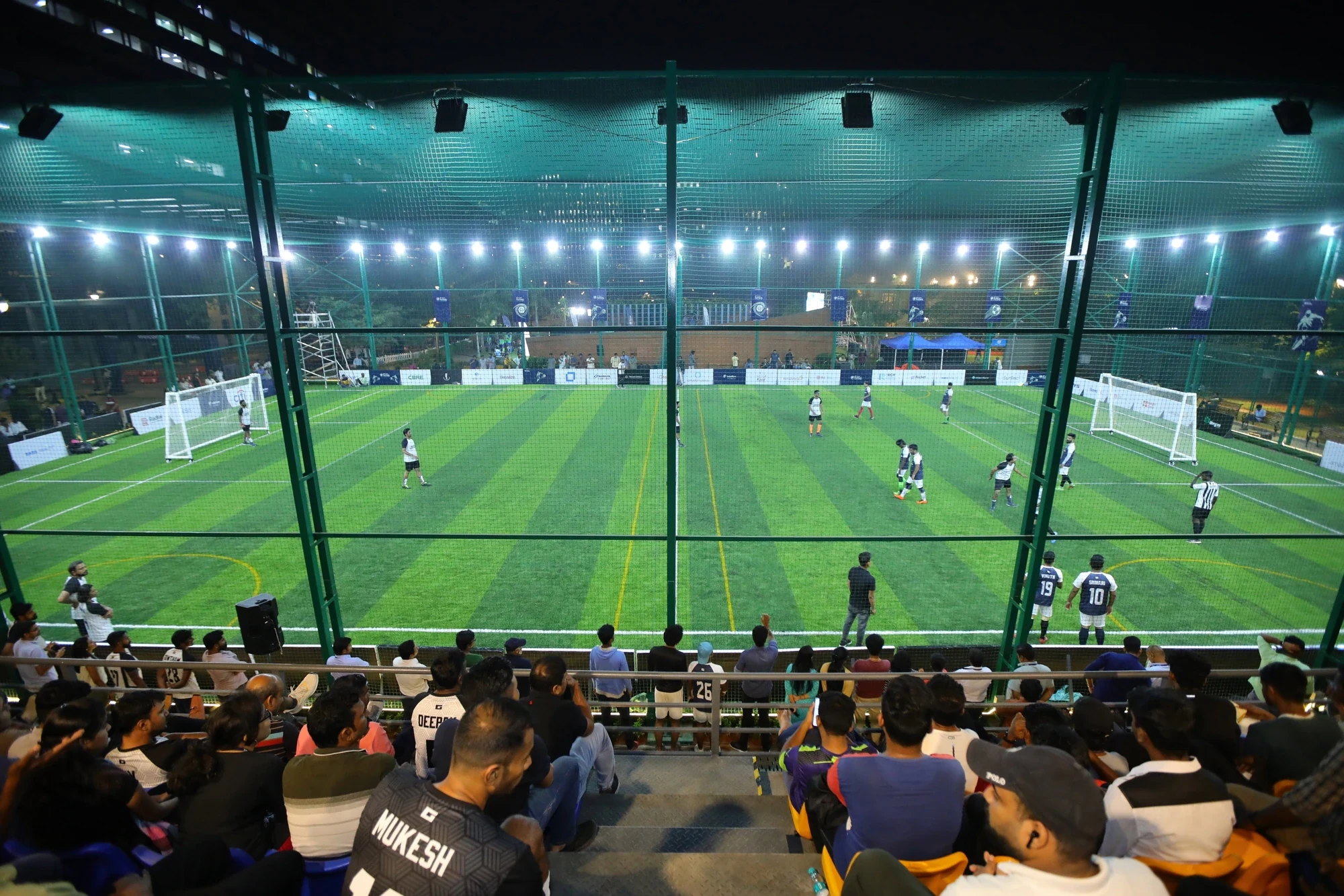 Night match under floodlights viewed from packed stands — Intellion Futsal League Season 2