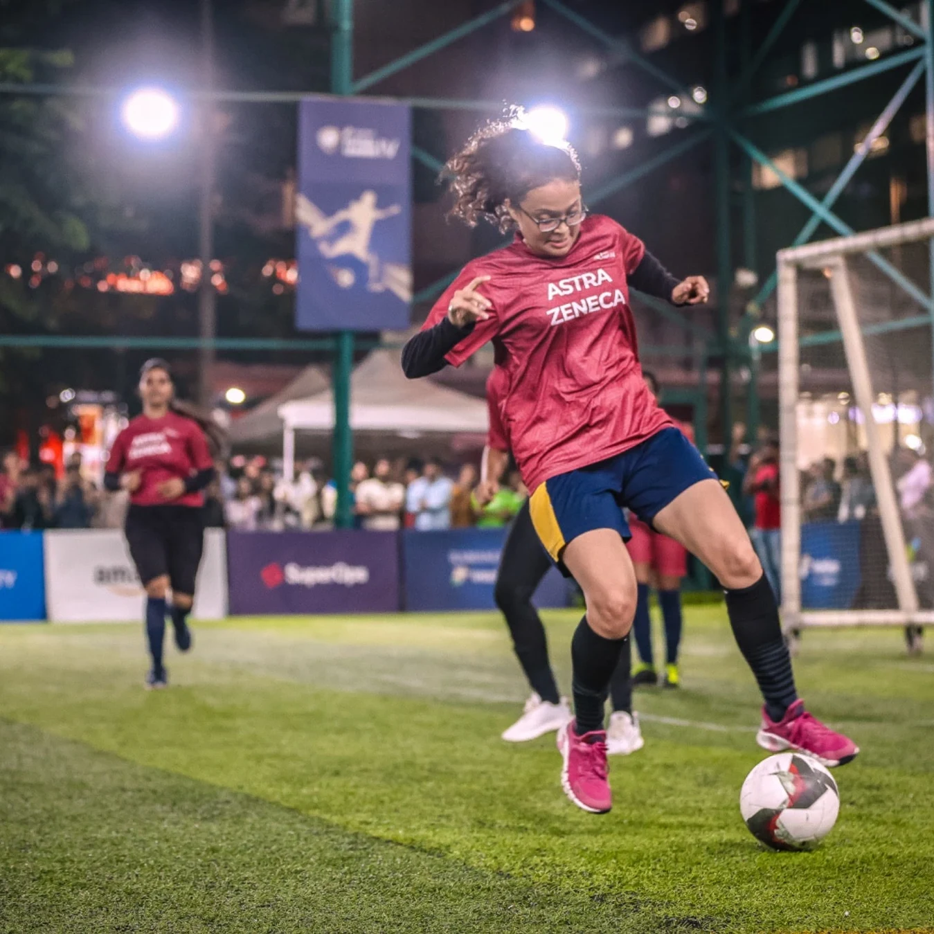 Women's league match under floodlights — AstraZeneca player on the ball at Intellion Futsal League IV
