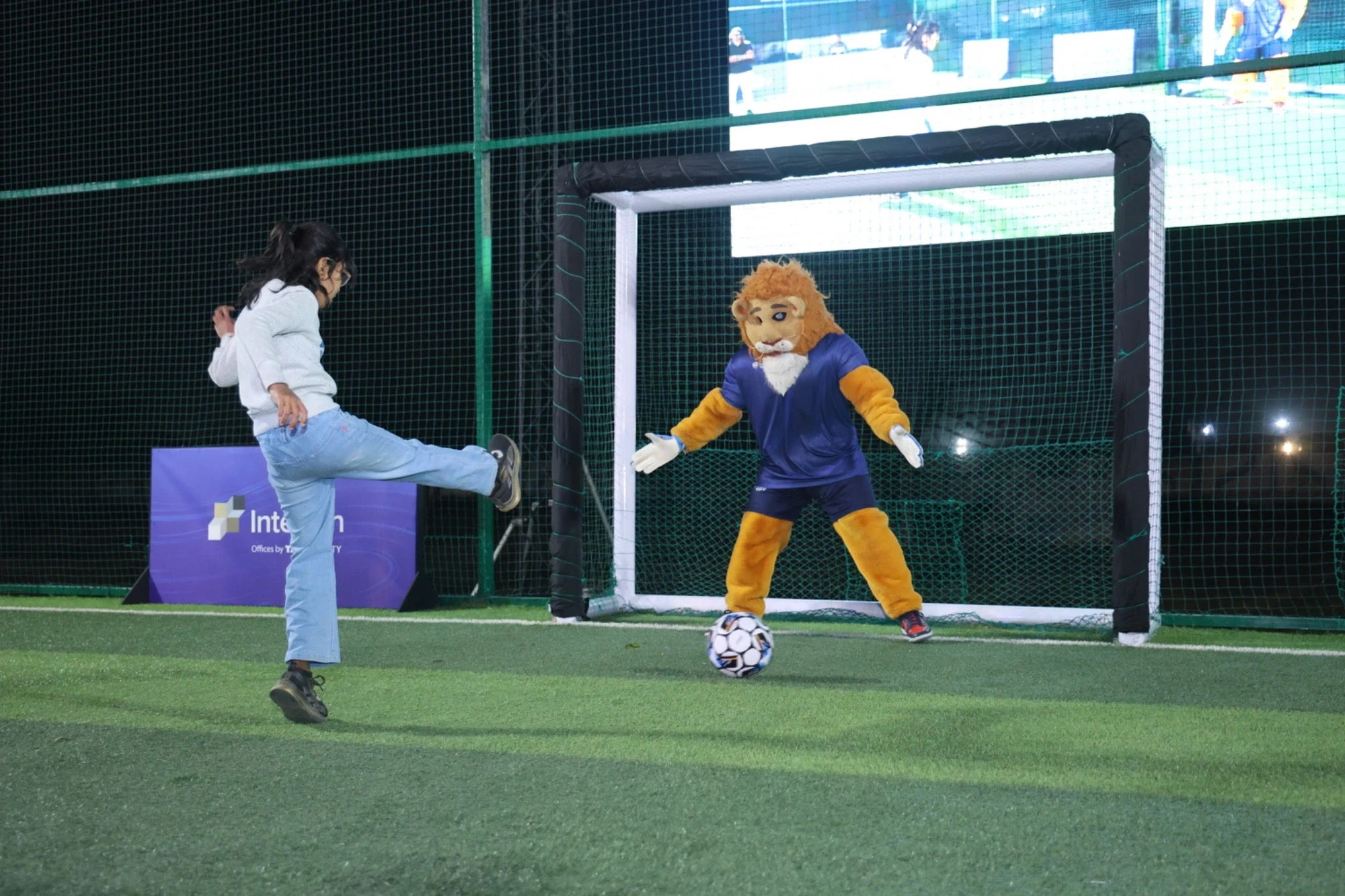 Leo the mascot guarding goal as a young fan takes a penalty at the Season 5 fan engagement zone