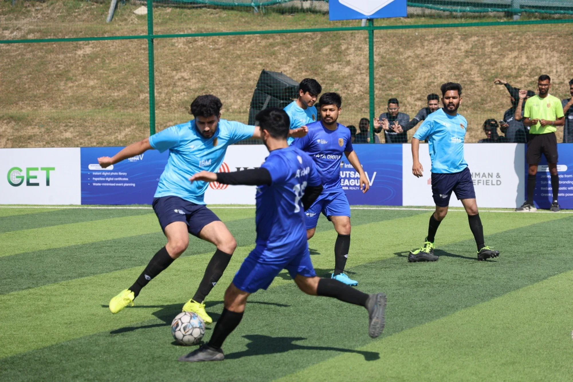 Season 5 league match — IBM and Tata Digital players contesting the ball by the branded boards