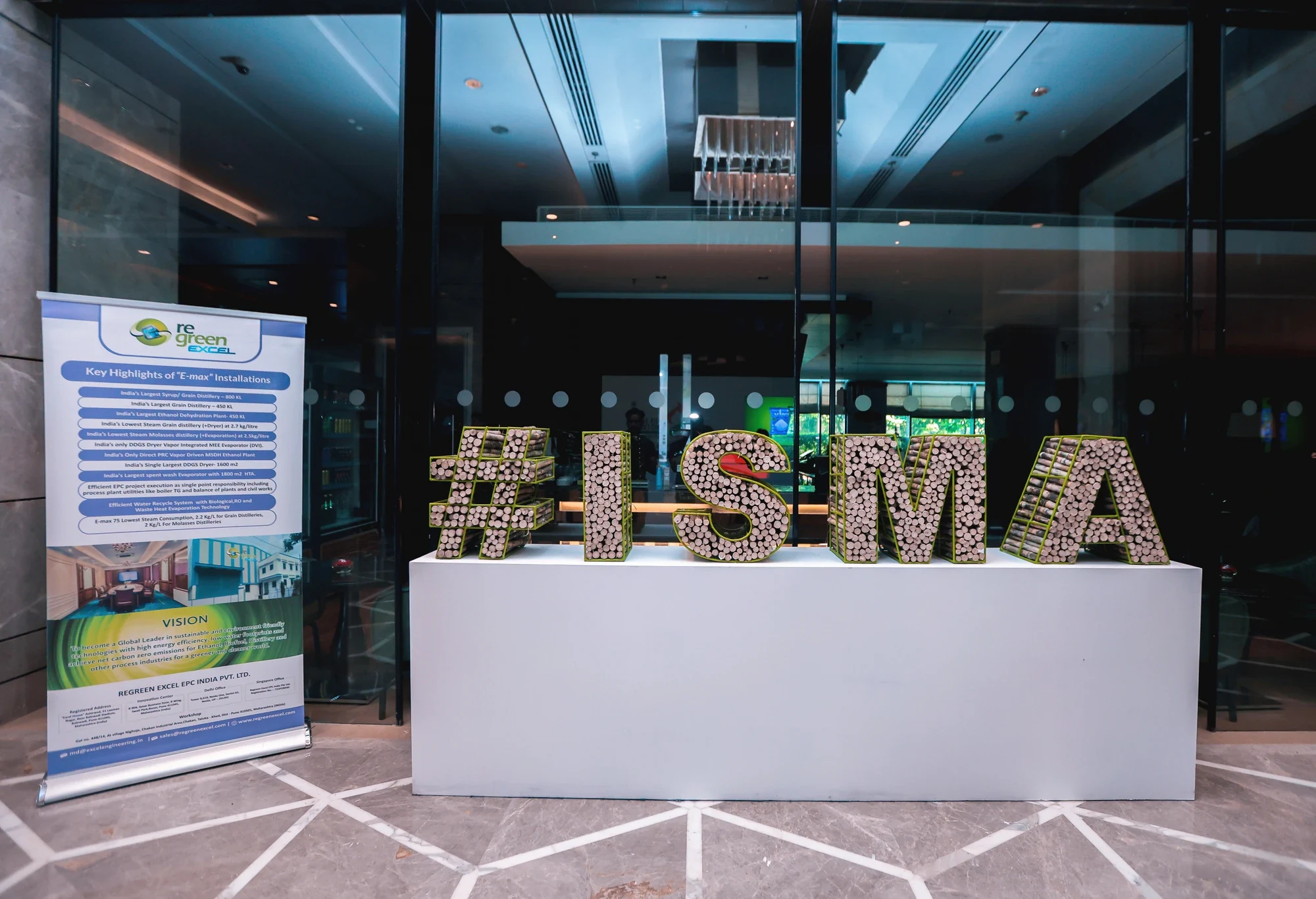 #ISMA bottle-cap letter installation with sponsor standee at the conference expo
