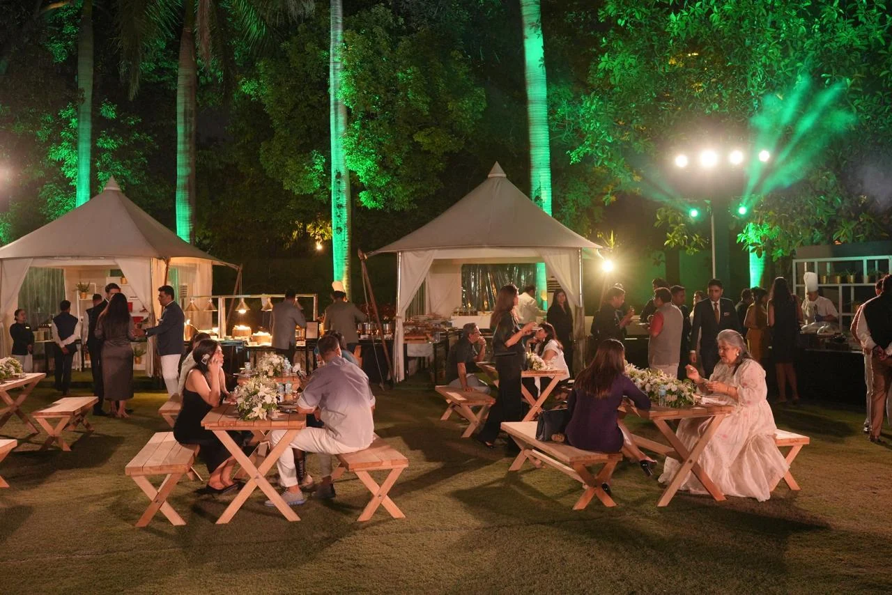 Guests dining on the lantern-lit lawn between pagoda bars