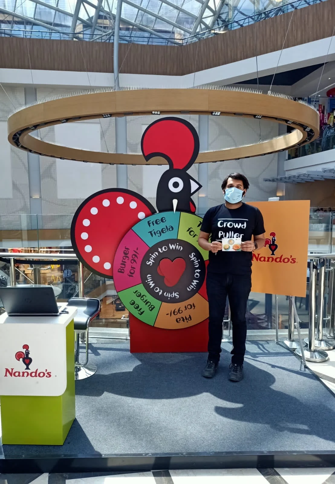 Winner with his prize card at the Spin to Win wheel under the mall's golden ring