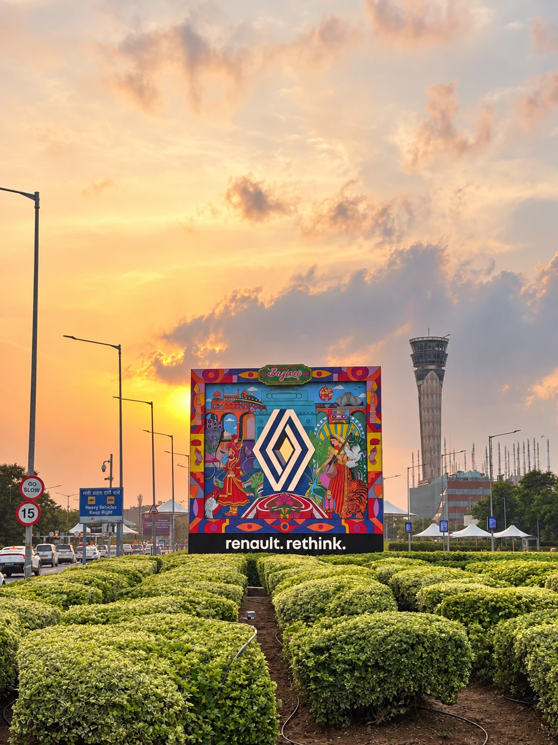 Renault rethink installation at IGI Airport against a golden sunset, with manicured hedges and the air traffic control tower