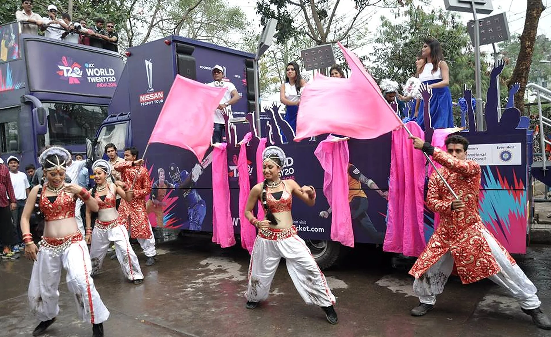 Dancers with pink flags performing in front of the ICC World Twenty20 Nissan Trophy Tour bus