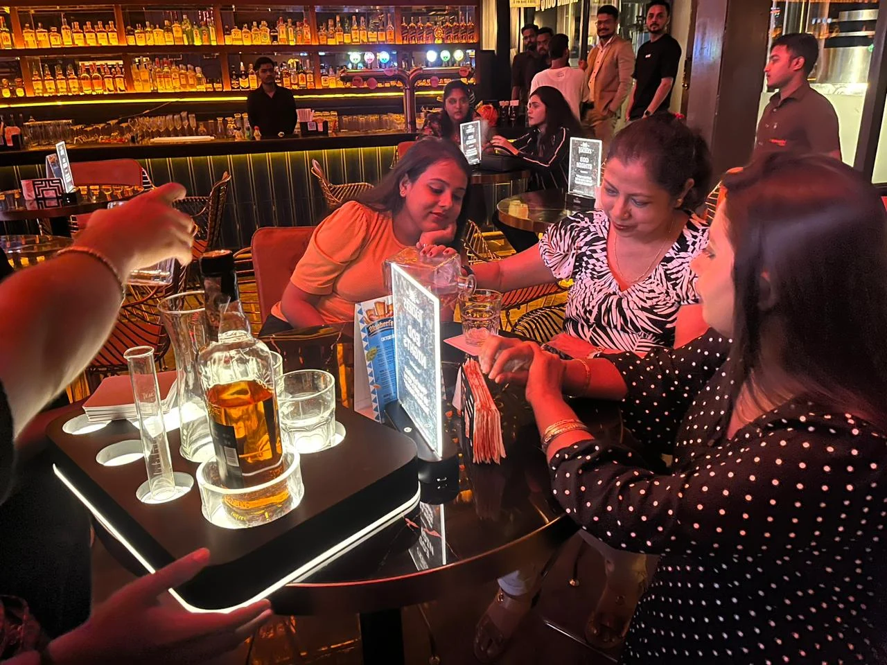 Guests trying the Barry 30 pour challenge at the bar with the illuminated serve tray