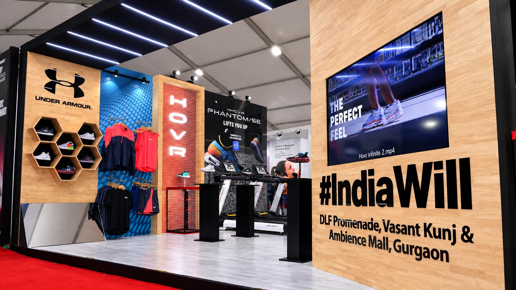 Under Armour booth with HOVR neon sign, hexagonal shoe wall and #IndiaWill branding
