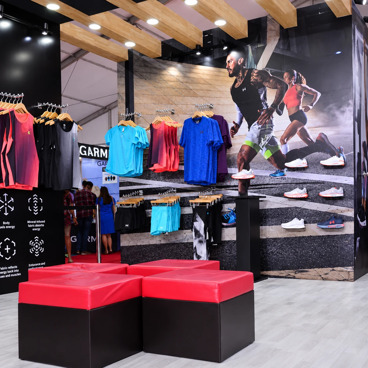 Under Armour apparel racks and red seating cubes at the expo