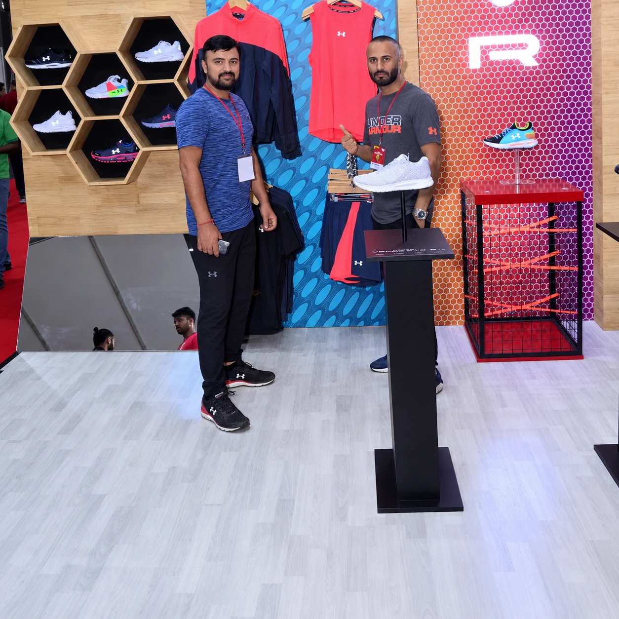 Hexagonal shoe wall and neon R display at the Under Armour expo