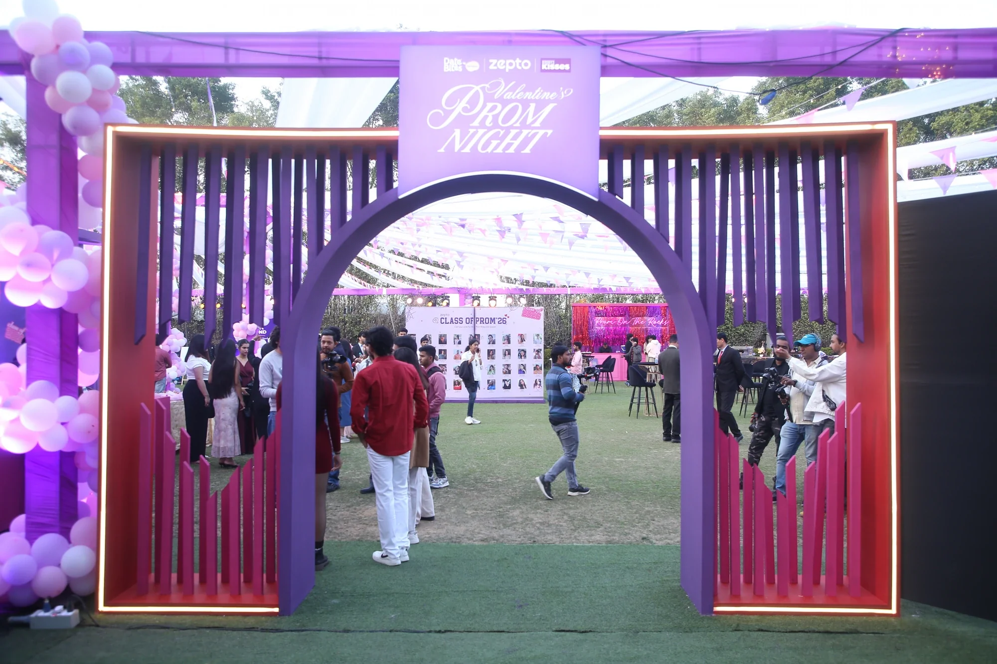 Zepto Valentine's Prom Night entrance — illuminated purple arch welcoming guests onto the lawn