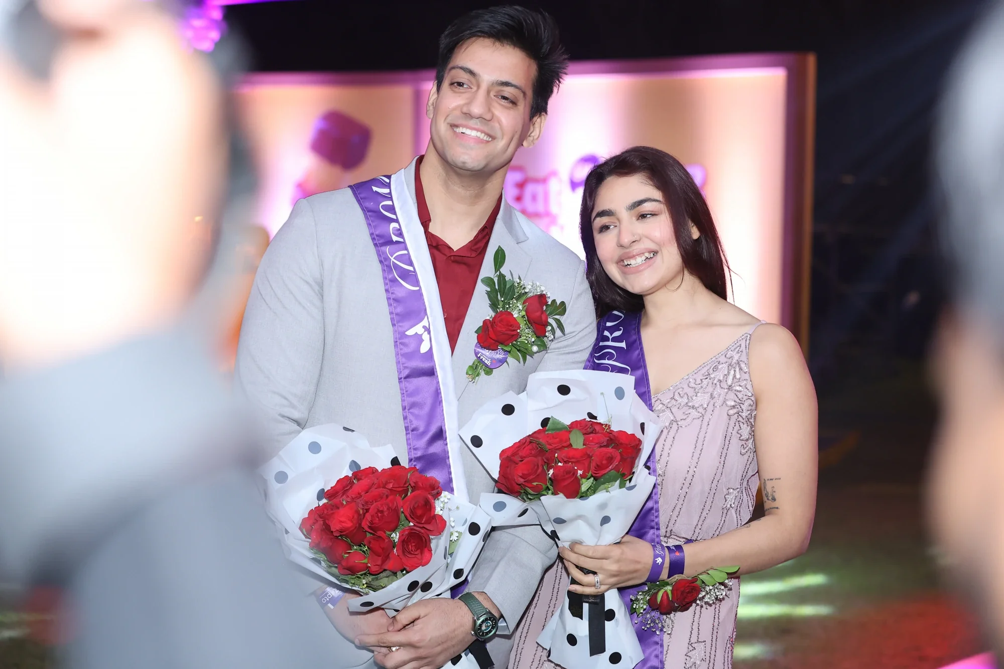 Prom king and queen crowned with sashes and red rose bouquets