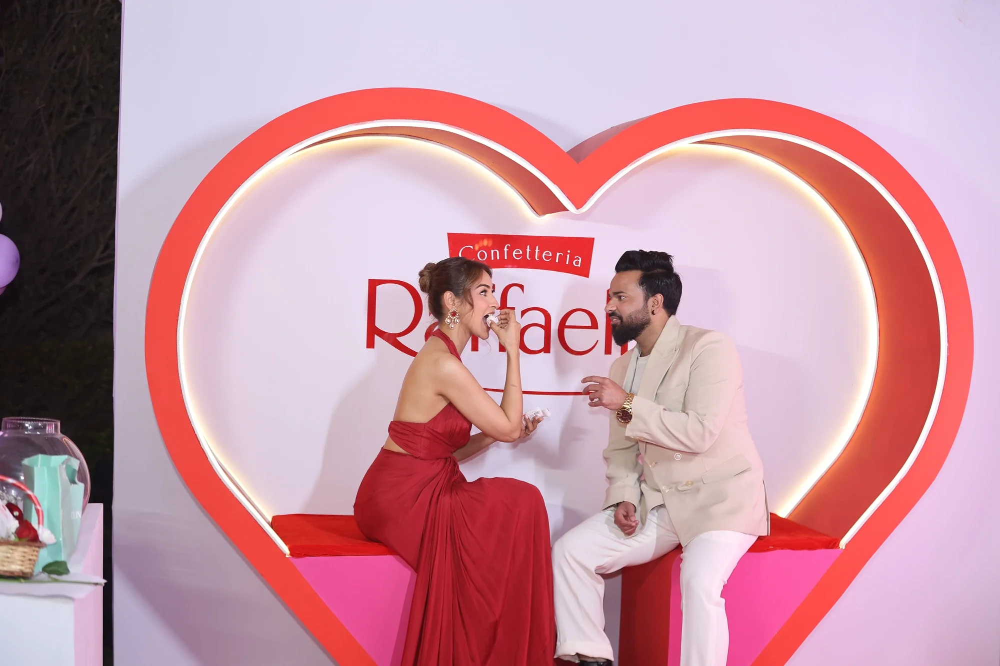 Couple sharing a Raffaello moment inside the glowing heart-shaped photo installation